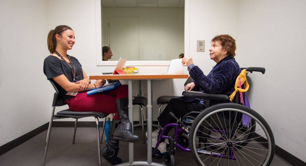 student talking to senior in wheelchair