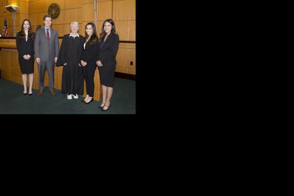 Five people smile in a courtroom