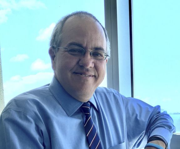 A close up image of a man standing by a window 