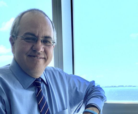 A close up image of a man standing by a window 