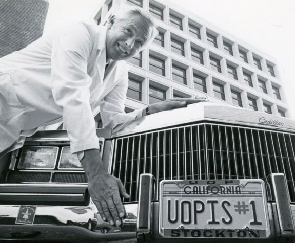 man with car with license plate that reads "uopis#1"