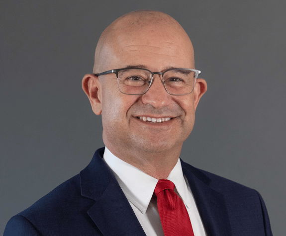 A man wearing a suit smiles for a photo 
