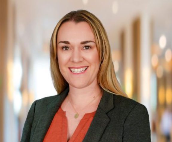 A woman wearing a suit smiles for a photo indoors