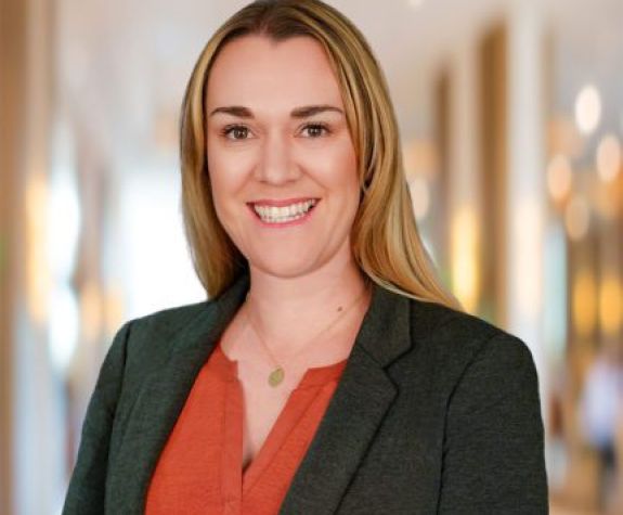 A woman wearing a suit smiles for a photo indoors