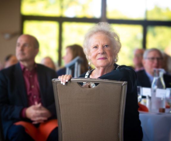 Judy Chambers, seated and looking over the back of a chair