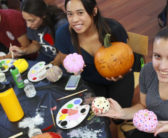 Pre-pharmacy students painting pumpkins 