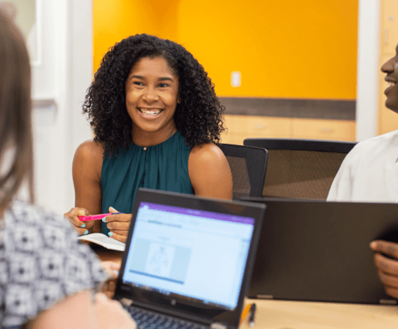 People sitting around a laptop computer and smiling