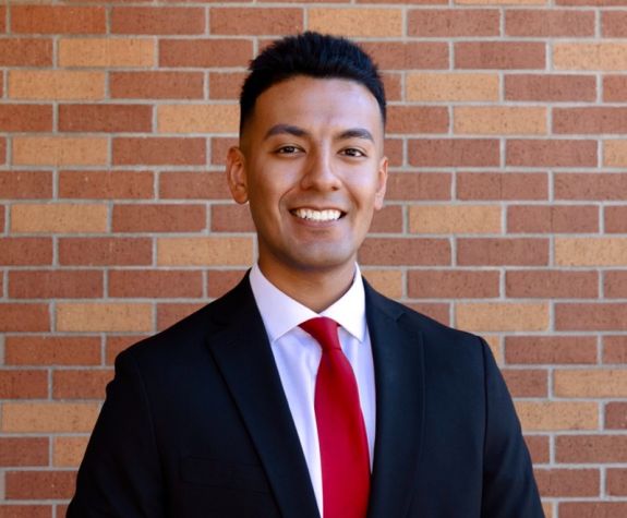 A portrait of a man wearing a suit in front of a brick wall