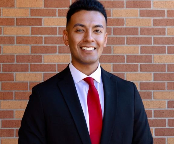 A portrait of a man wearing a suit in front of a brick wall