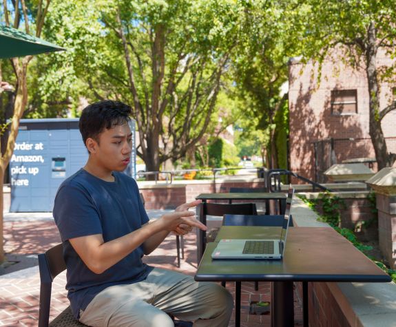 Student on campus using his laptop for a video call.