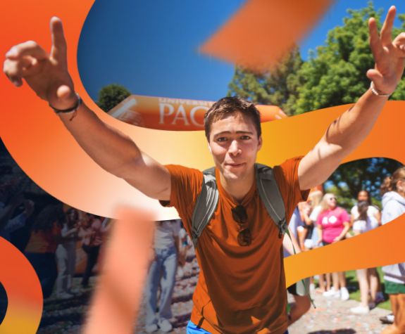 student in an orange tshirt with arms raised