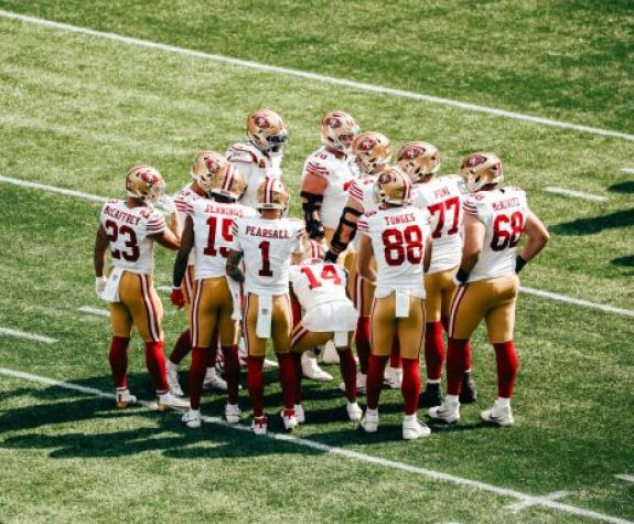 the 49ers huddle on a field