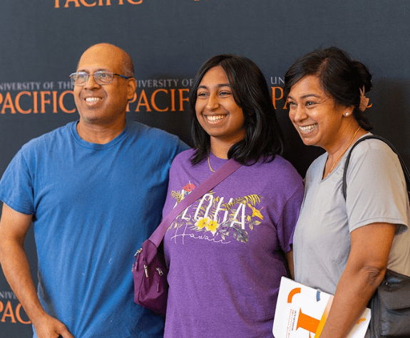 parents and child pose in front of University of the Pacific banner