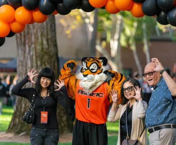 Powercat and a family standing under a balloon arch