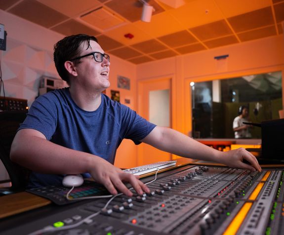 A student with a sound mixing board in University of the Pacific's recording studio