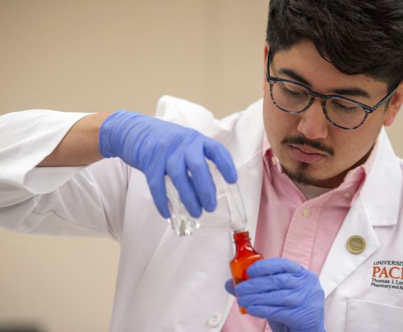 Man wearing white coat working in a compounding lab