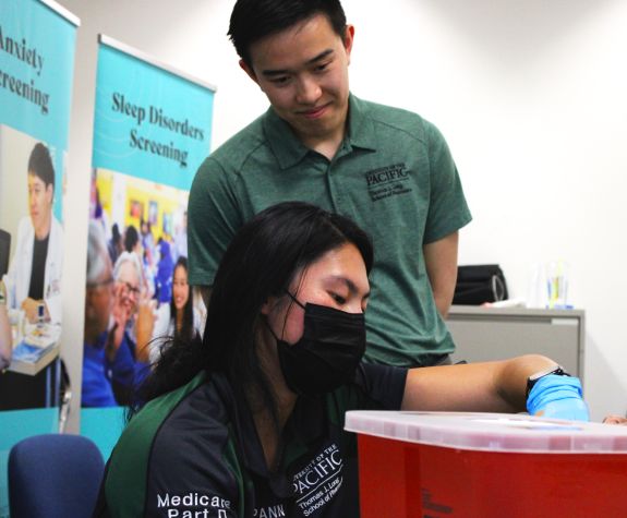 Two pharmacy students with a patient at a health care outreach clinic