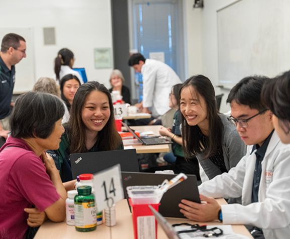 Pharmacist and students with a patient at a health fair
