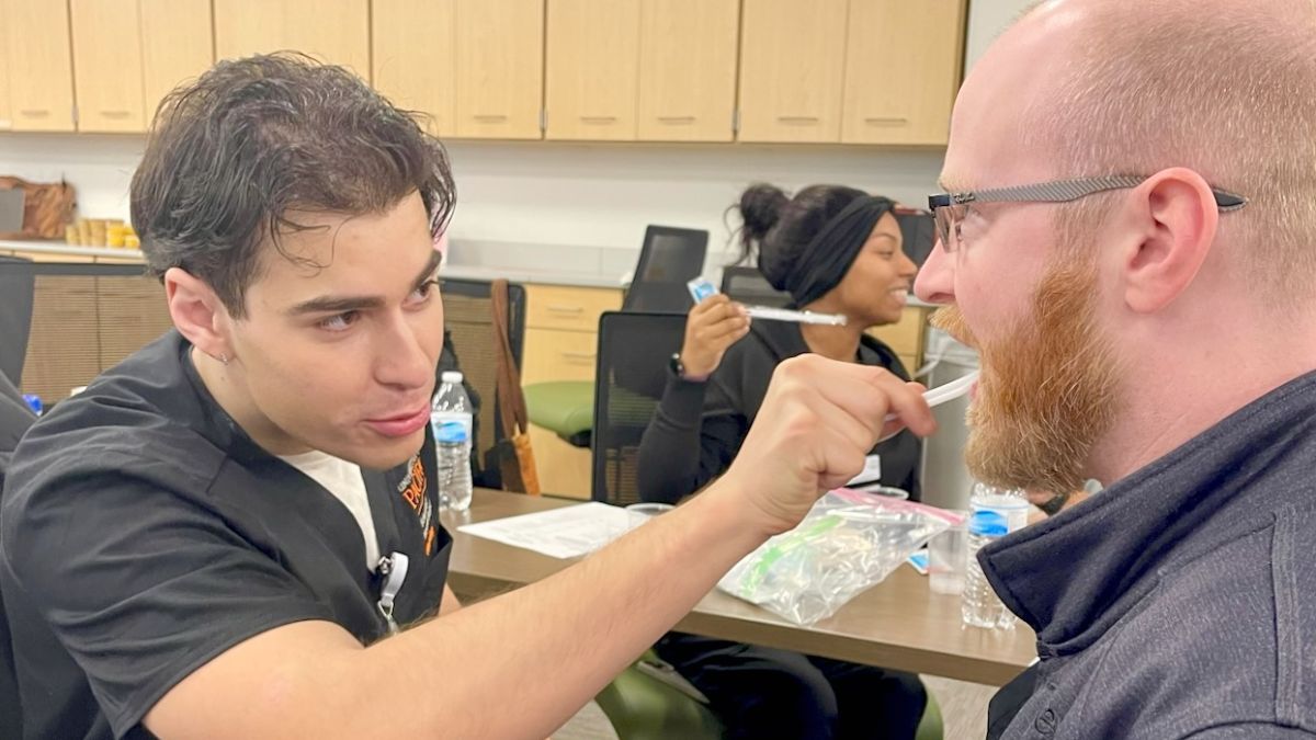 One student is practicing brushing another student's teeth.