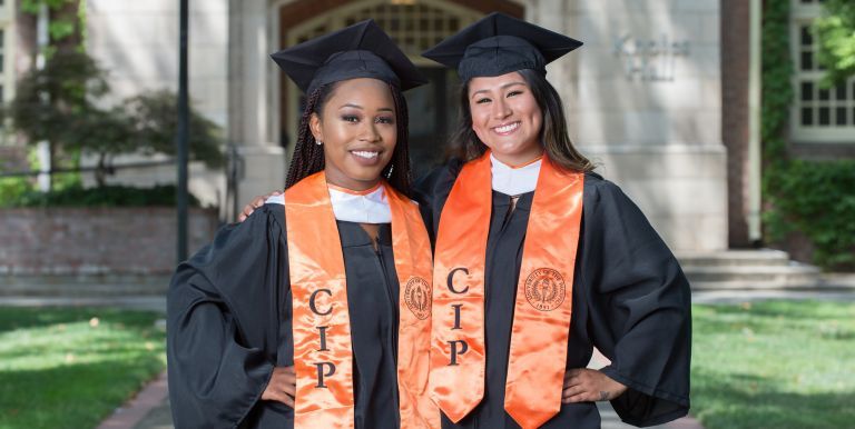 two Community Involvement Program scholars in commencement regalia 
