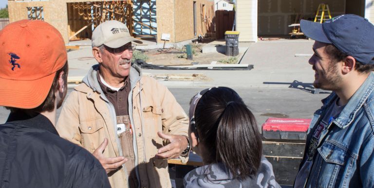 CIP scholars build a fence together while volunteering for the Habitat for Humanity.
