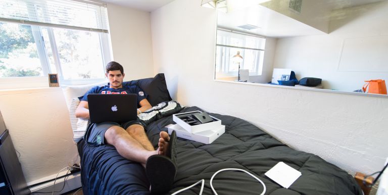student in dorm looking at laptop