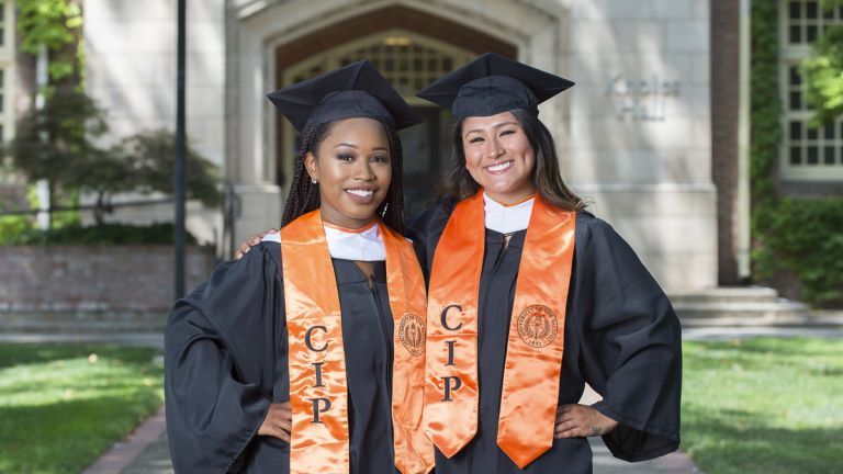 two Community Involvement Program scholars in commencement regalia 