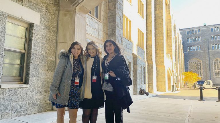 smiling students standing in front of West Point building