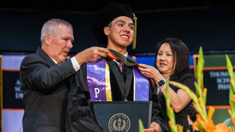 PharmD graduate is hooded by his legacy alumni parents at Commencement