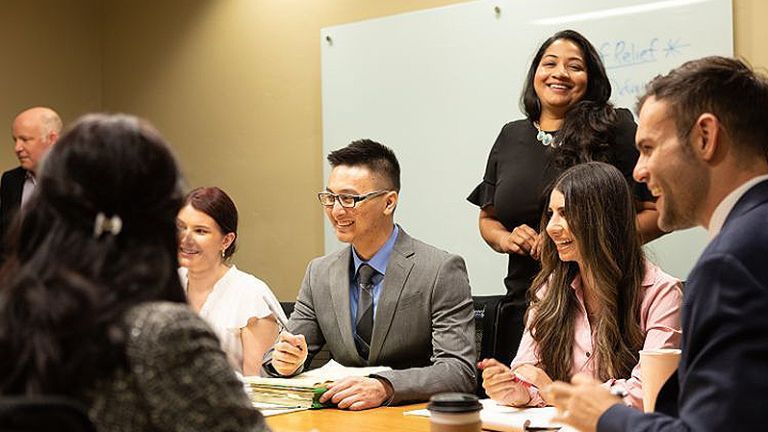 several people sit around a table, smiling and talking