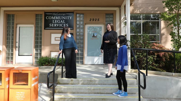 Three women speak to each other outside of the clinics building