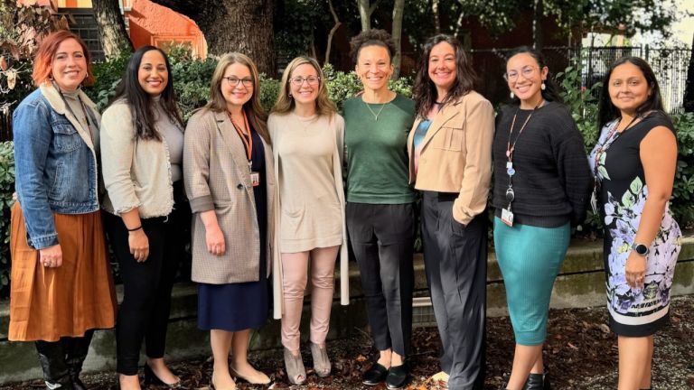 Image shows seven members of the SHS Occupational Therapy Faculty standing with Alyson Stover, president of the American Occupational Therapy Association. 