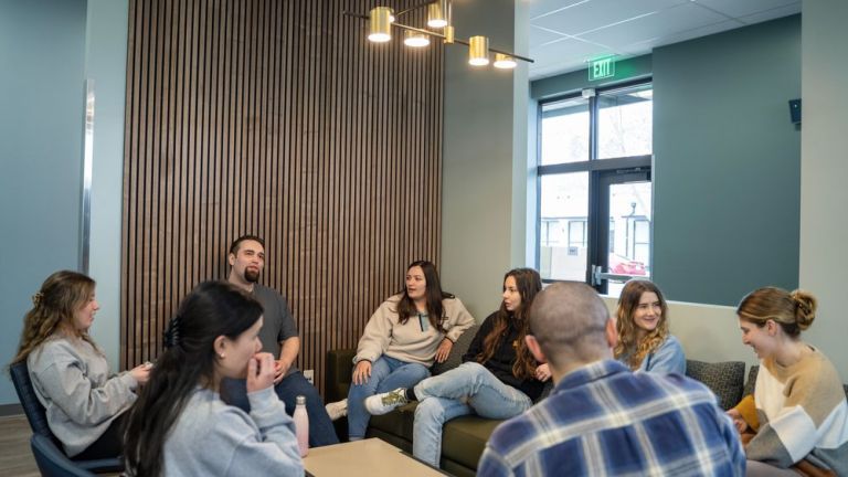 Photo shows a group of students talking while sitting in the student lounge. 
