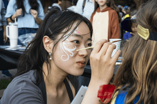 a student paints a design on a child's face
