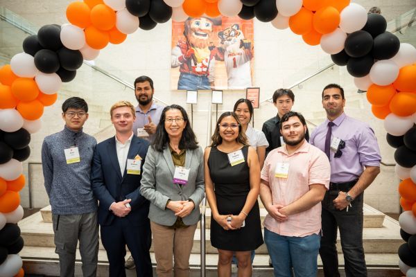a group of students stand under a balloon arch