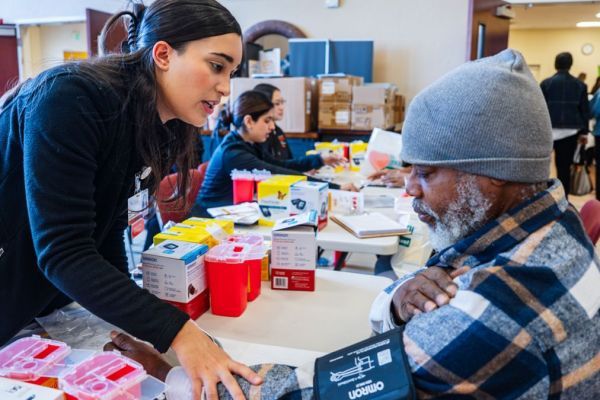 a student helps a participant in a health fair