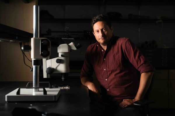 Chris Torres sits next to a microscope