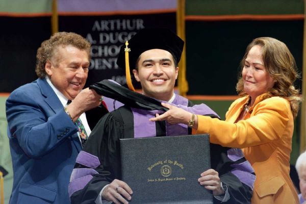 student with faculty at commencement