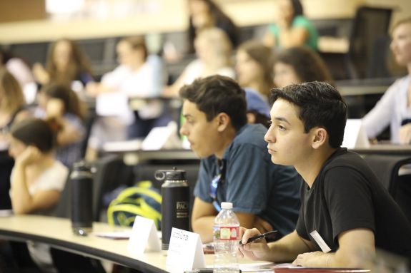 Two men sit in a classroom at a lecture.