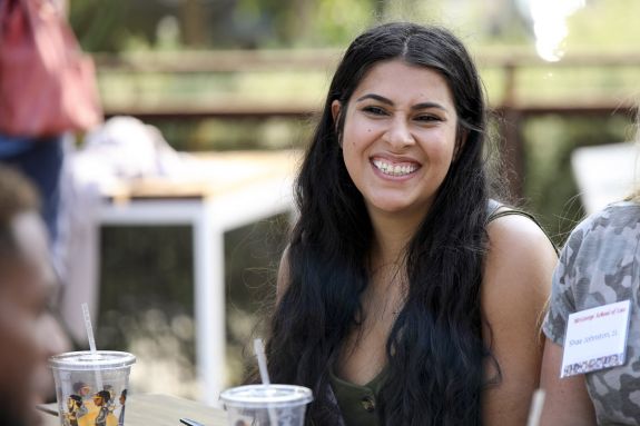 A woman sits outside and smiles in conversation.