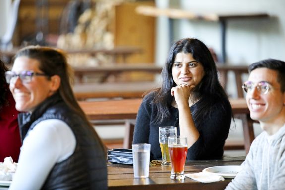 A woman sits on a bench with other law students at a brewery.