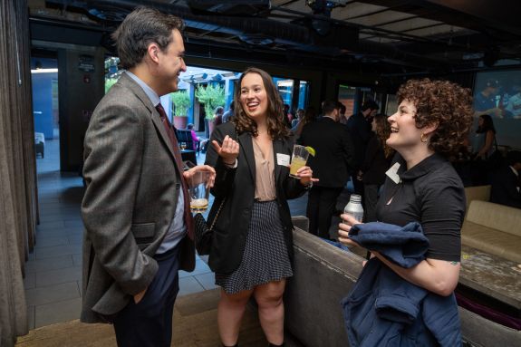 Two women talking to a man in a black suit 