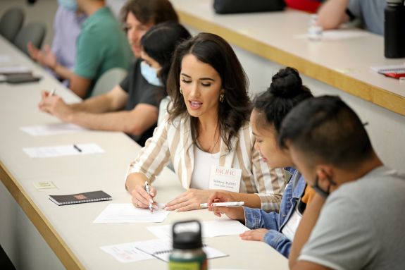 Woman in white shirts shows other students info on paper 