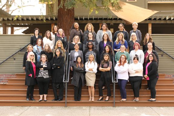 A group of 30 women pose for a photo on a staircase