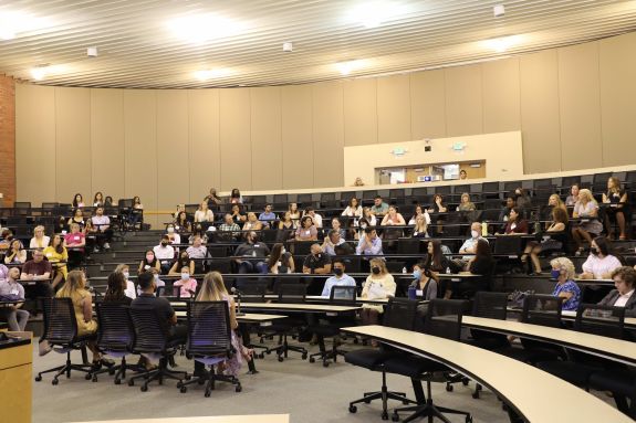 crowd of people listening to four people in from of the room 