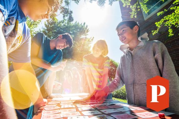 Smiling students playing outside with cards