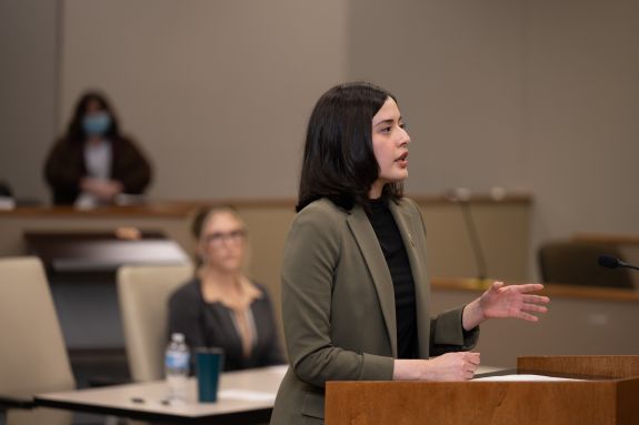 Woman in green suit jackets speaks to court