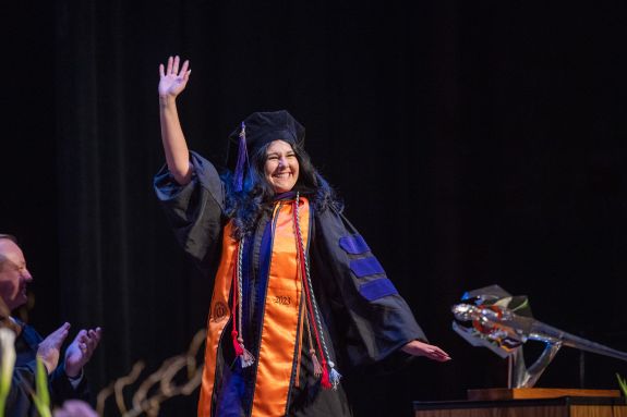 A graduate waves as they cross the stage