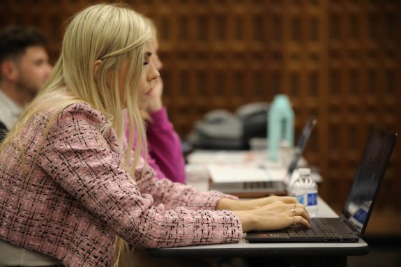 Woman in pink suit types on a laptop 