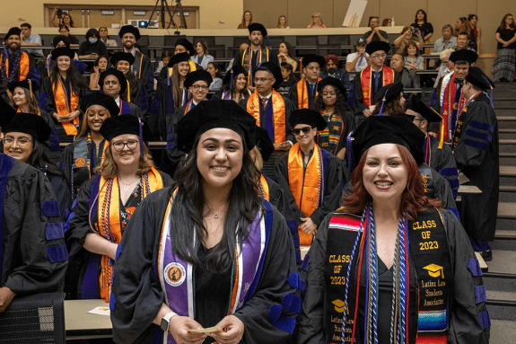 Students posing for a photo wearing graduation attire.